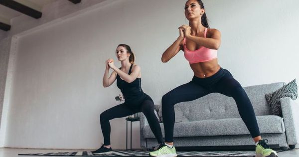 This may contain: two women doing yoga poses in front of a couch