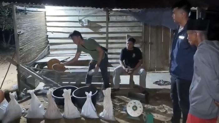 PENAMPUNGAN PASIR TIMAH - Anggota Satreskrim Polres Bangka Selatan memeriksa sejumlah karung berisi pasir timah saat penggerebekan di sebuah rumah di Desa Paku, Kecamatan Payung, Senin (2/3/2026) malam. Dalam operasi tersebut, polisi menemukan ratusan kilogram pasir timah beserta alat penimbangan dan penyaringan serta mengamankan seorang perempuan.
