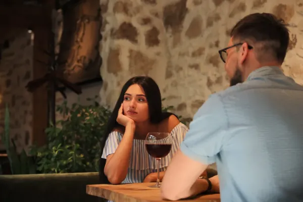 Young woman looking bored while on a date with a man at a cafe.