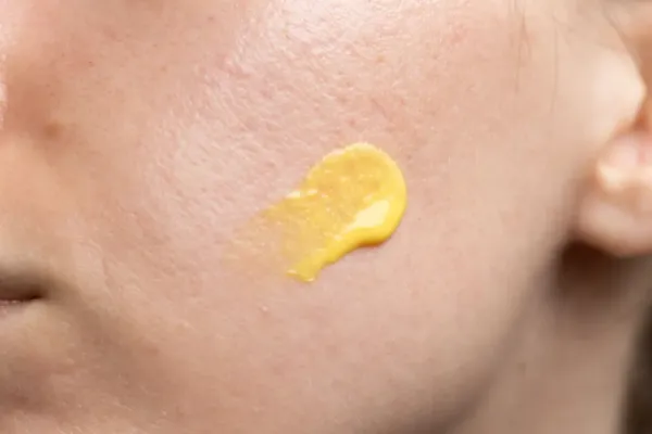 A tight shot of a person's skin texture, with a swipe of skincare product.