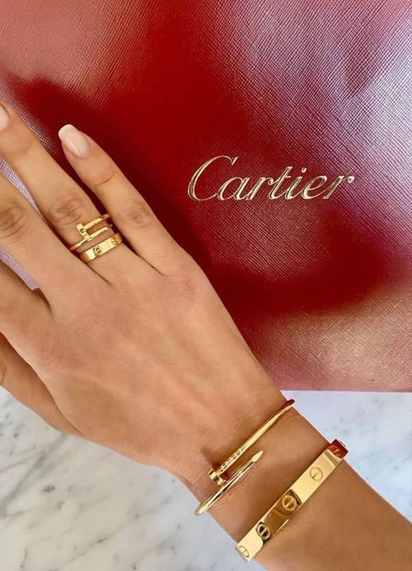 This may contain: a woman's hand with two gold bracelets on her wrist and a red purse