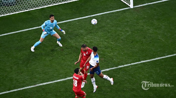 Gelandang Inggris Jude Bellingham (kanan) mencetak gol pertama timnya selama pertandingan sepak bola Grup B Piala Dunia 2022 Qatar antara Inggris dan Iran di Stadion Internasional Khalifa di Doha. Senin (21/11/2022). (Jewel SAMAD/ AFP)