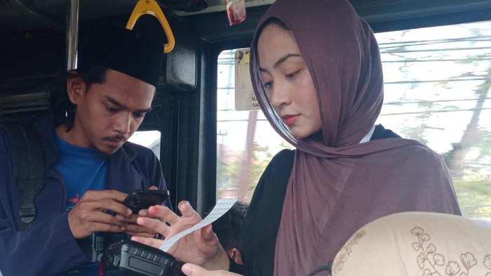 PRAMUGARI CANTIK - Pramugari Bus Trans Jatim koridor 7, Mahmudah Wirda Tillah melayani penumpang dengan menyodorkan karcis di layanan gratis masa lebaran hari ini, Sabtu (21/3/2026)