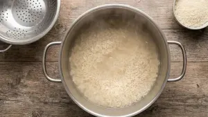 Boiling rice in a large pot of water until slightly soft, then draining and letting the rice cool without overcooking.