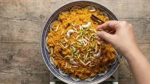 Garnishing the prepared Zarda pulao with sliced ​​almonds and serving it warm or slightly cooled