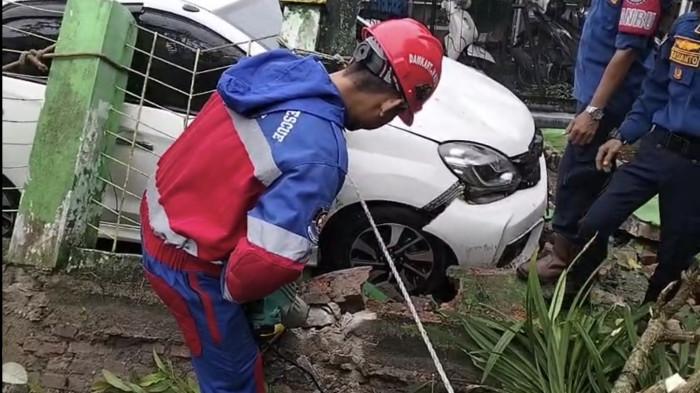 PAGAR ROBOH - Mobil milik warga Gang Kepinis I, Kota Jambi, tertimpa pagar rumah yang roboh akibat hujan deras, Minggu (22/3/2026) dini hari. 