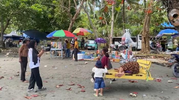 WISATA PANTAI RAMAI-Sejumlah wisatawan menikmati suasana Pantai Batu Oge di Desa Batu Oge, Kecamatan Pedongga, Kabupaten Pasangkayu, Senin (23/3/2026). Pada hari ketiga Idul Fitri 1447 H, kawasan wisata ini dipadati pengunjung yang bersantai bersama keluarga, memanfaatkan fasilitas ayunan, serta berburu jajanan di lapak pedagang setempat.