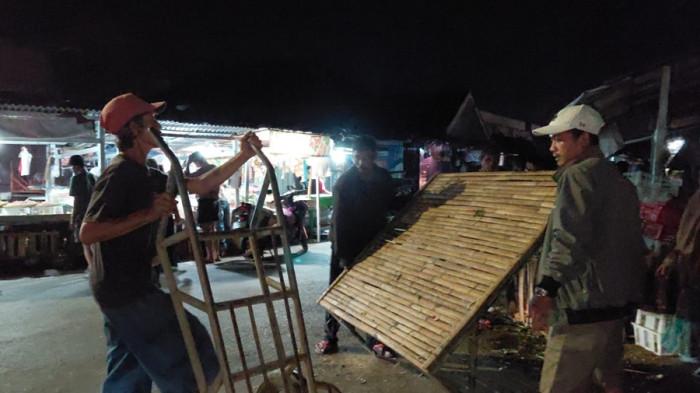 PINDAHKAN DAGANGAN - Pedagang di Jalan Vihara Pasar Wage membereskan lapak dagangannya, Minggu (22/3/2026) malam. Mereka bersiap untuk dipindahkan ke area dalam lantai 2 Pasar Wage setelah 25 tahun berjualan di badan jalan.