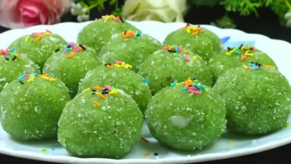 Green lauki laddus topped with silver varq, placed on a wooden board, with one cut open showing the filling inside.