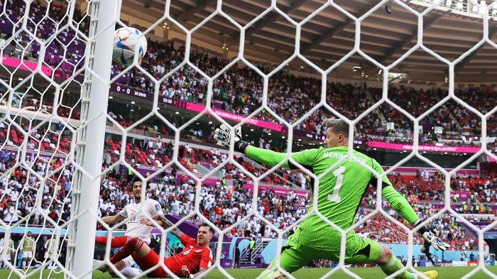 Penyerang Timnas Iran, #20 Sardar Azmoun (kiri) melakukan tembakan yang membentur tiang gawang melewati penjaga gawang Timnas Wales, #01 Wayne Hennessey (kanan) yang berusaha melakukan penyelamatan untuk mengamankan bola dalam laga sepak bola Grup B Piala Dunia 2022 Qatar antara Wales melawan Iran di Stadion Ahmad Bin Ali, di Al-Rayyan, sebelah barat Doha, Qatar, Jumat (25/11/2022) waktu setempat. AFP/ADRIAN DENNIS