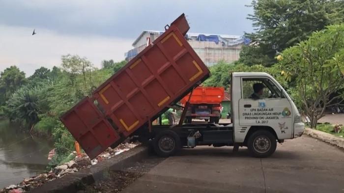 VIRAL MEDIA SOSIAL - Tangkapan layar video viral yang merekam truk tipper kecil membuang sampah ke Kali Pesanggrahan di kawasan TPU Tanah Kusir, Kebayoran Lama, Jakarta Selatan. Kepala Unit Penanganan Sampah Badan Air (UPSBA) DLH DKI Jakarta, Dadang Cahya Rusdiana, menjelaskan aktivitas kendaraan dump pickup yang terlihat dalam unggahan itu merupakan bagian dari operasional resmi penanganan sampah badan air, bukan pembuangan ke sungai.