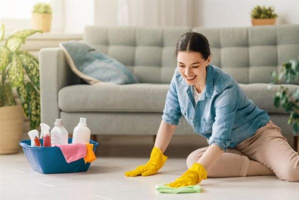 This may contain: a woman cleaning the floor in her living room with yellow rubber gloves and sponges