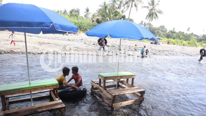 PEMANDIAN LUMIN- Dua orang anak menikmati aliran sungai Lubuk Minturun dengan menaiki ban dalam di Kecamatan Koto Tangah, Kota Padang, Sumatera Barat, Sabtu (28/3/2026).
