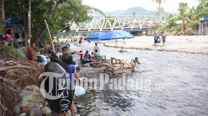 PEMANDIAN LUMIN- Warga berenang dengan menggunakan ban dalam di aliran sungai Lubuk Minturun, Kecamatan Koto Tangah, Kota Padang, Sumatera Barat, Sabtu (28/3/2026).