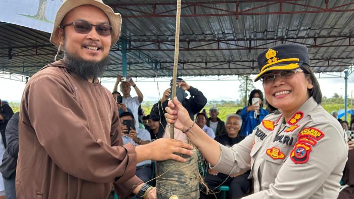 Kapolres Samosir AKBP Rina Sry Nirwana Tarigan menerima bibit pohon secara simbolis dari Pastor sebelum penanaman di perbukitan Partukko Naginjang, Kecamatan Harian, Samosir, Sabtu (28/3/2026). Kegiatan ini menjadi bagian dari aksi penghijauan kawasan Danau Toba.