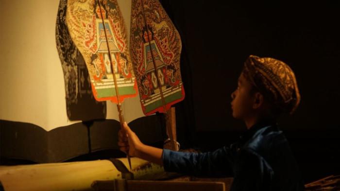 DALANG CILIK- Ilustrasi seorang dalang cilik sedang memainkan wayangnya.