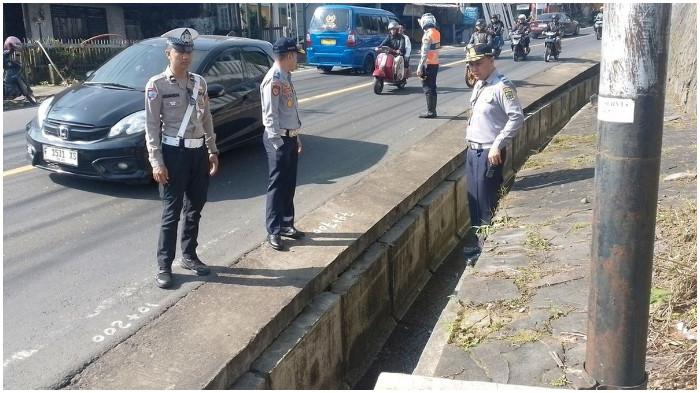 Sejumlah petugas meninjau kondisi saluran drainase di jalan raya Cipanas, Cianjur