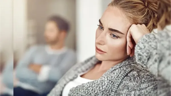 woman and man sitting together and woman keepin her hand on head