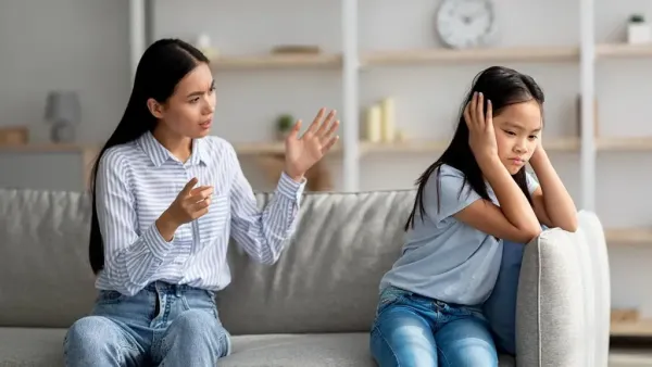 girl is keeping hands on her ears and mom talking to her