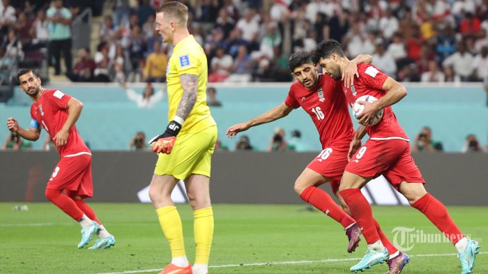 Penyerang Iran Mehdi Taremi (kanan) merayakan dengan gelandang Iran Mehdi Torabi (16) setelah dia mencetak gol melewati kiper Inggris Jordan Pickford selama pertandingan sepak bola Grup B Piala Dunia Qatar 2022 antara Inggris dan Iran di Stadion Internasional Khalifa di Doha. Senin (21/11/2022). (Fadel Senna/AFP)