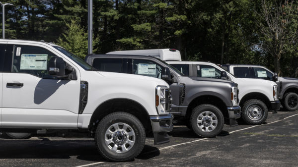 Side view of Ford Super Duty pickup trucks lined up on a dealer lot.