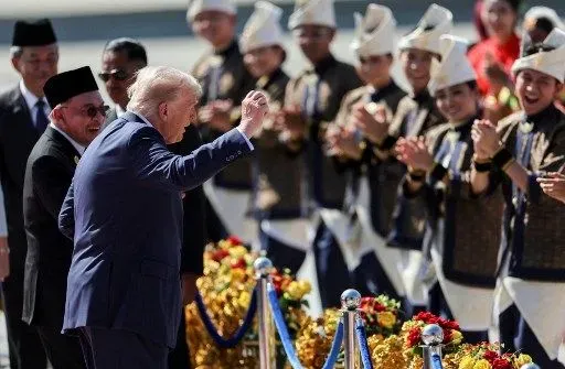 US President Donald Trump (C) joins performers for a dance during the welcome ceremony next to Malaysia's Prime Minister Anwar Ibrahim (L) as he arrives on Air Force One at Kuala Lumpur International Airport in Kuala Lumpur on October 26, 2025. US President Donald Trump arrived in Malaysia on October 26 on the first leg of an Asian tour that will include high-stakes trade talks with Chinese counterpart Xi Jinping. (Photo by Hasnoor Hussain / POOL / AFP)
