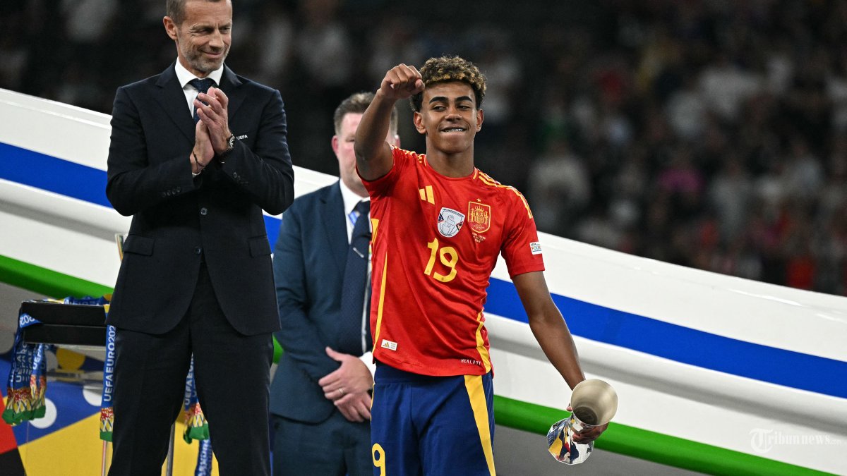 Penyerang Spanyol #19 Lamine Yamal merayakan dengan trofi Pemain Muda Terbaik di samping Presiden UEFA Aleksander Ceferin setelah memenangkan pertandingan sepak bola final UEFA Euro 2024 antara Spanyol dan Inggris di Olympiastadion di Berlin pada 14 Juli 2024. (Photo by JAVIER SORIANO / AFP)