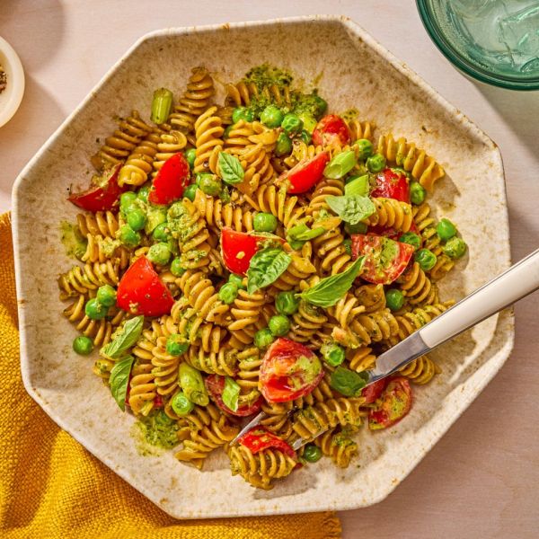 Pesto pasta salad with cherry tomatoes and peas in a bowl with a fork Credit: Ali Redmond