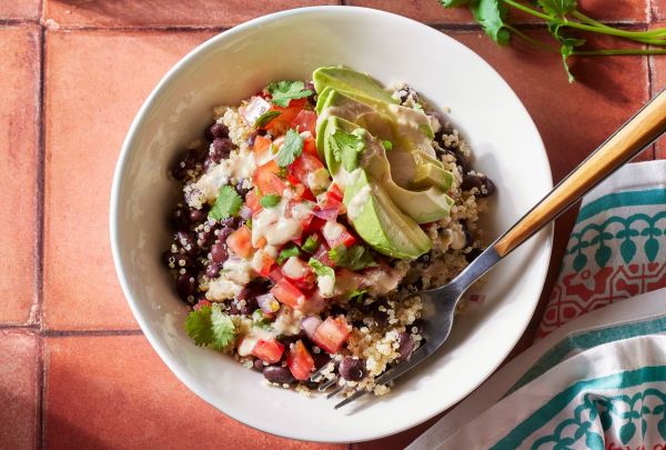 Overhead view of a white bowl of Black Bean-Quinoa Bowl recipe on a reddish brown tile tabletop Credit: Photography: Carson Downing, Food Stylist: Holly Dreesman, Prop Stylist: Gabe Greco