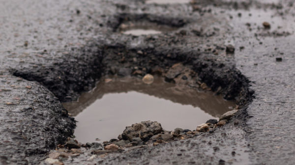 A deep road pothole filled with water.