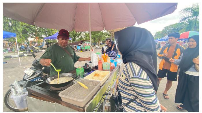 MELAYANI - Iman (40), pedagang telur gulung, melayani pembeli di Jalan Yos Sudarso, tepat di depan pujasera, Palangka Raya, Minggu (5/4/2026). Kenaikan harga plastik sejak Ramadan mulai dirasakan pedagang kecil.