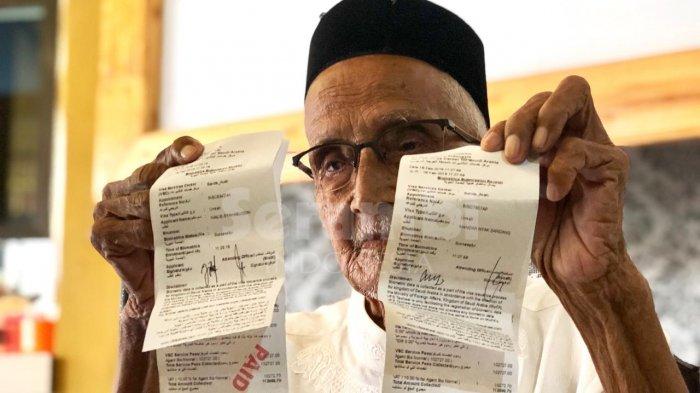 Nyak Sandang (91) memperlihatkan tiket umrah pemberian Presiden Jokowi dalam konferensi pers di Banda Aceh, Senin (18/2/2019).