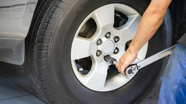 Auto mechanic using Torque wrench to inspect the wheel nuts