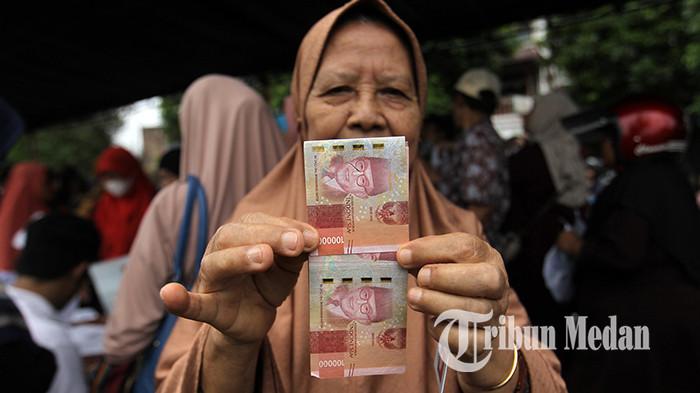 Warga menunjukkan uang tunai seusai menerima bantuan sosial di Lapangan Sejati, Medan, Senin (24/11/2025). Sebanyak 2.755 Kepala Keluarga dari tiga kelurahan di Kecamatan Medan Johor menerima BLT dari program Kemensos untuk kesejahteraan rakyat (Kesra) dengan besaran Rp 900.000 per KK.