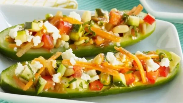 Cucumber boats filled with chopped vegetables, sprouts, sev, and crumbled paneer served on a plate.