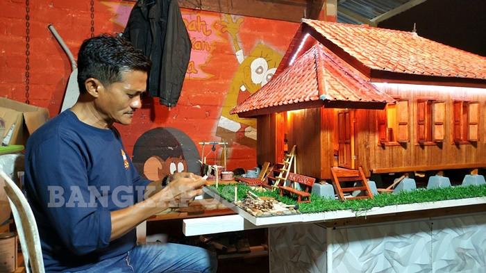 Pegiat Seni dan Budaya Kabupaten Bangka Selatan, Yoel Chaidir ketika tengah mengerjakan miniatur rumah adat Pelideh di kediamannya di Kelurahan Teladan, Kecamatan Toboali, Sabtu (11/4/2026). Miniatur tersebut ia kerjakan selama sebulan terakhir.