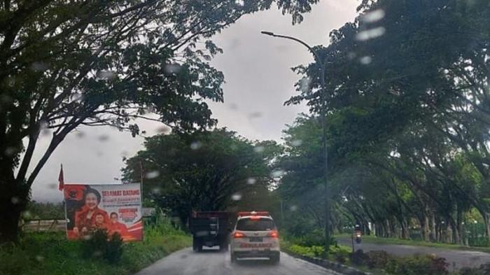 INFO CUACA - Ilustrasi. Suasana saat hujan ringan mengguyur sepanjang Jalan Soekarno, Minahasa Utara, Sulawesi Utara, Jumat (20/2/2026). Sejumlah wilayah di Sulawesi Utara berpotensi diguyur hujan hari ini, Minggu (12/4/2026).