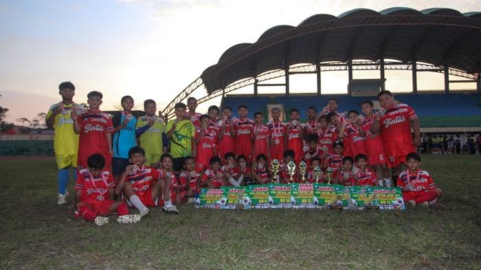DOMINASI - Skuat SSB Bintar Kelompok merayakan keberhasilan mereka dalam ajang Pelangi Cup 2026 di Stadion Rimba Pelawan, Kecamatan Damar, Senin (13/4/2026). Selain meraih podium tertinggi, tim ini juga sukses menyapu bersih gelar individu seperti pemain terbaik dan pencetak gol terbanyak melalui metode pembinaan yang mengedepankan kegembiraan bermain bola.