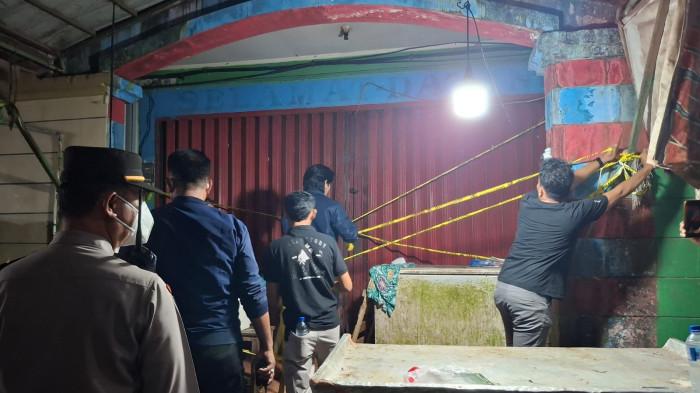 OLAH TKP - Tampak personel Reskrim Polres Tarakan memasang police line di pintu ruko TKP tempat IS ditemukan, Senin (13/4/2026).
