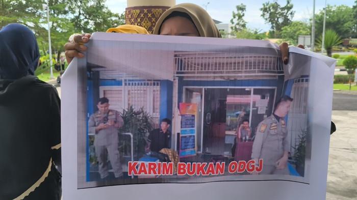 AKSI UNJUK RASA - Adik pengamen Karim bernama Sri Sukma memperlihatkan foto di kantor Dinas Sosial usai unjuk rasa di Balai Kota, Kelurahan Aie Pacah, Kecamatan Koto Tangah, Kota Padang, Rabu (15/4/2026). Sri sebut kasus kematian kakaknya belum menemukan titik terang hingga saat ini.