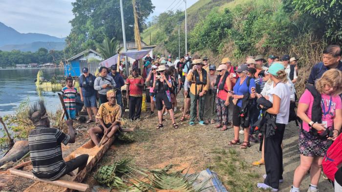 WISATAWAN ASING – 70 Wisatawan asing mendatangi masyarakat adat di Kampung Yobeh, Distrik Sentani, Kabupaten Jayapura, Papua pada Rabu, (15/4/2026). Di sana mereka disuguhkan dengan demo pangkur sagu, penampilan tarian Isosolo, dan pahatan miniatur dan keliling Danau Sentani. 