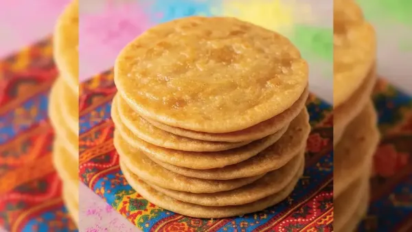 Stack of golden, crispy puris placed on a colorful traditional cloth.