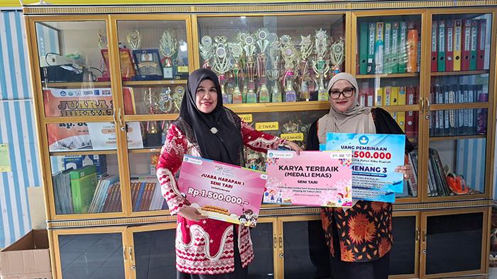 FOTO BERSAMA - Kepala SD Negeri 1 Beureuenun, Pidie, Cut Zainabon SPd MSi (kiri) dan Syarifah Zaimah, SPd MSi, Gr (guru) pada Jumat (17/4/2026) berfoto bersama berlatar belakang sejumlah piala dan plakat diraih sekolah tersebut.