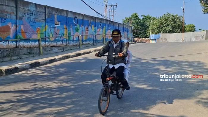 KAYUH SEPEDA - Abdul Azis, guru honorer di MI Nurul  l Islam 1 membonceng anaknya dengan sepeda menuju ke sekolah. Gaji kecil sebagai guru honorer membuatnya tak mampu membeli motor bekas sekalipun seusai motornya hilang.