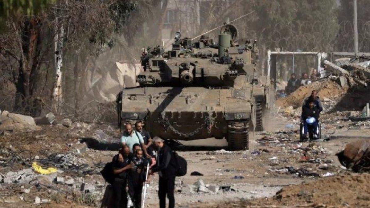 Warga Palestina di Gaza Utara, melewati tank Israel saat berupaya mengungsi menyelamatkan diri dari Gaza utara ke pinggiran selatan Kota Gaza, selama gencatan senjata empat hari, pada 24 November 2023.