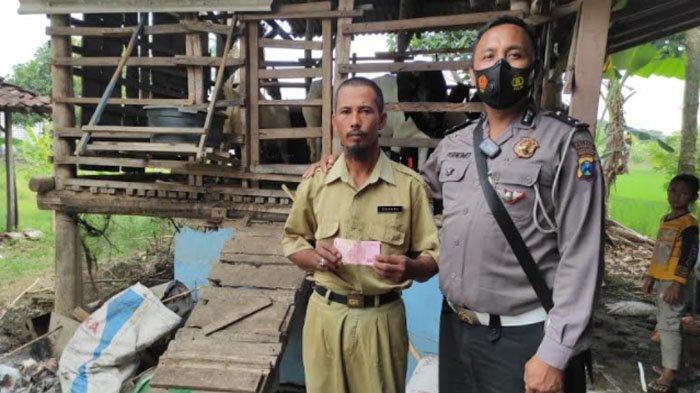 Anggota Satlantas Polres Lamongan Aipda Purnomo saat memberi bantuan untuk guru Suhari.
