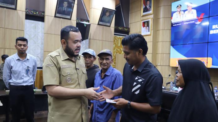 BANTUAN BENCANA - Wali Kota Padang Fadly Amran berfoto bersama penerima bantuan stimulan perbaikan rumah bagi warga terdampak bencana hidrometeorologi di Ruang Abu Bakar Ja’ar, Balai Kota Aia Pacah, Selasa (28/4/2026). Bantuan tersebut disalurkan kepada 55 kepala keluarga yang tersebar di empat kecamatan di Kota Padang.