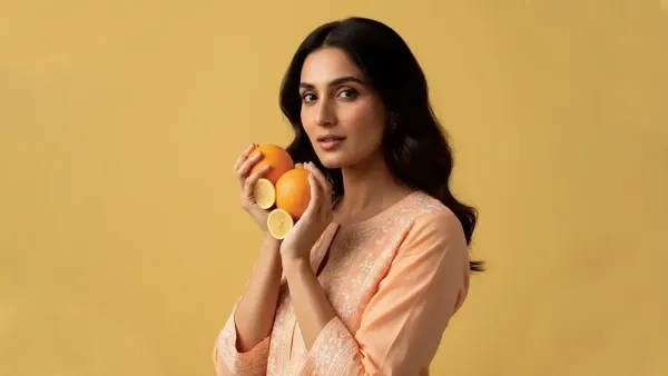 Woman holding oranges and lemon slices, symbolizing natural skincare and vitamin-rich beauty.