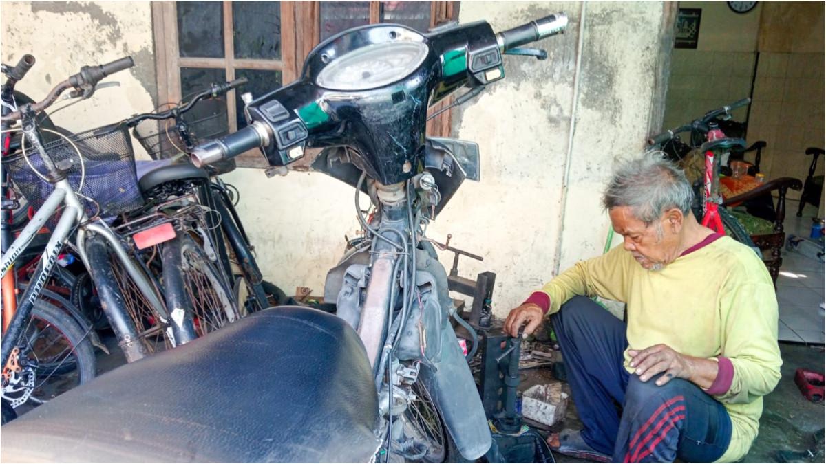 POTRET MBAH PARTO - Momen ketika Mbah Parto tengah menambal ban, Senin (6/4/2026).