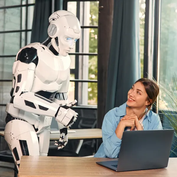 artifical intelligence robot looking at computer screen of female worker in office